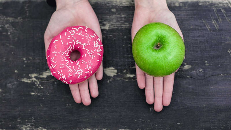 Hands showing choice between an apple or donut